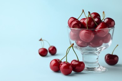Fresh ripe cherries on light blue background, space for text