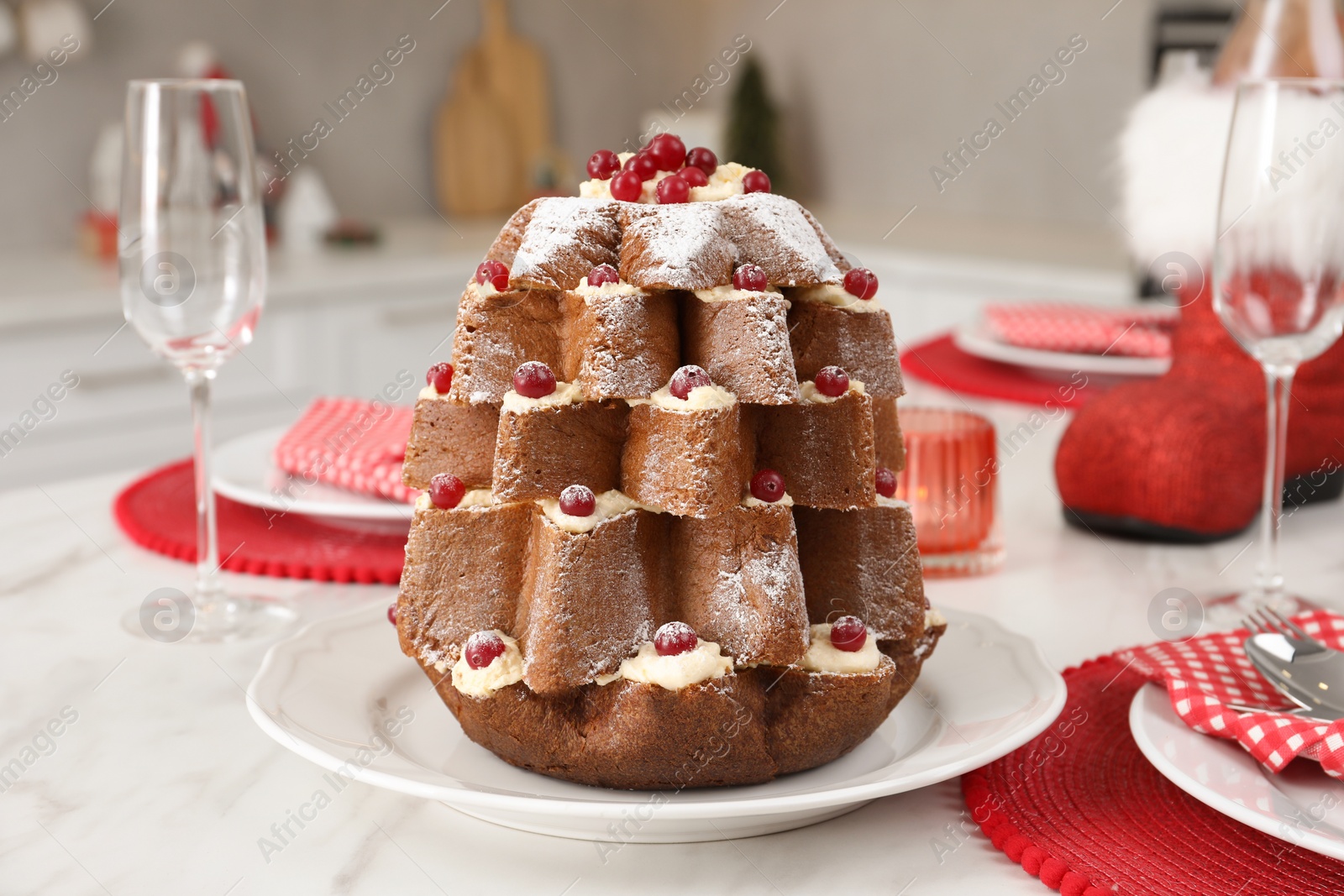 Photo of Delicious Pandoro Christmas tree cake decorated with powdered sugar and berries on white marble table