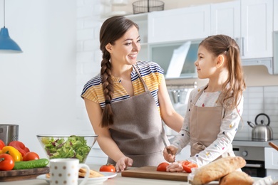 Photo of Young nanny with cute little girl cooking together in kitchen