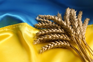 Photo of Ears of wheat on Ukrainian national flag, closeup. Space for text