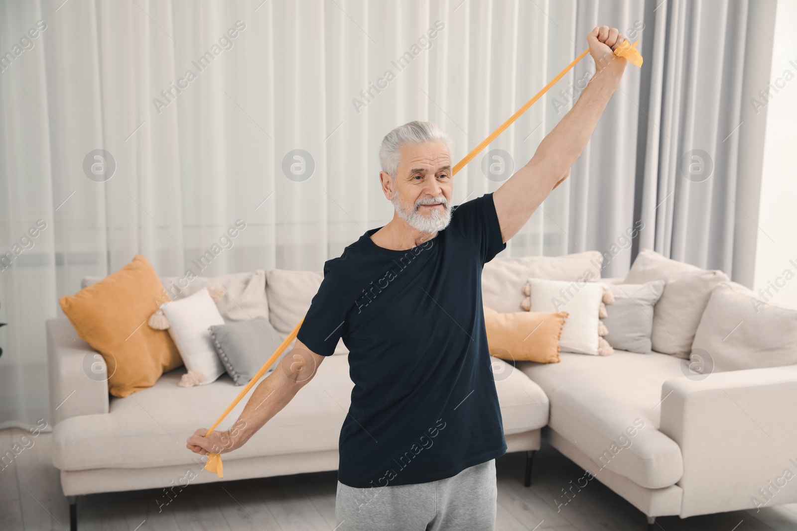 Photo of Senior man doing exercise with fitness elastic band at home