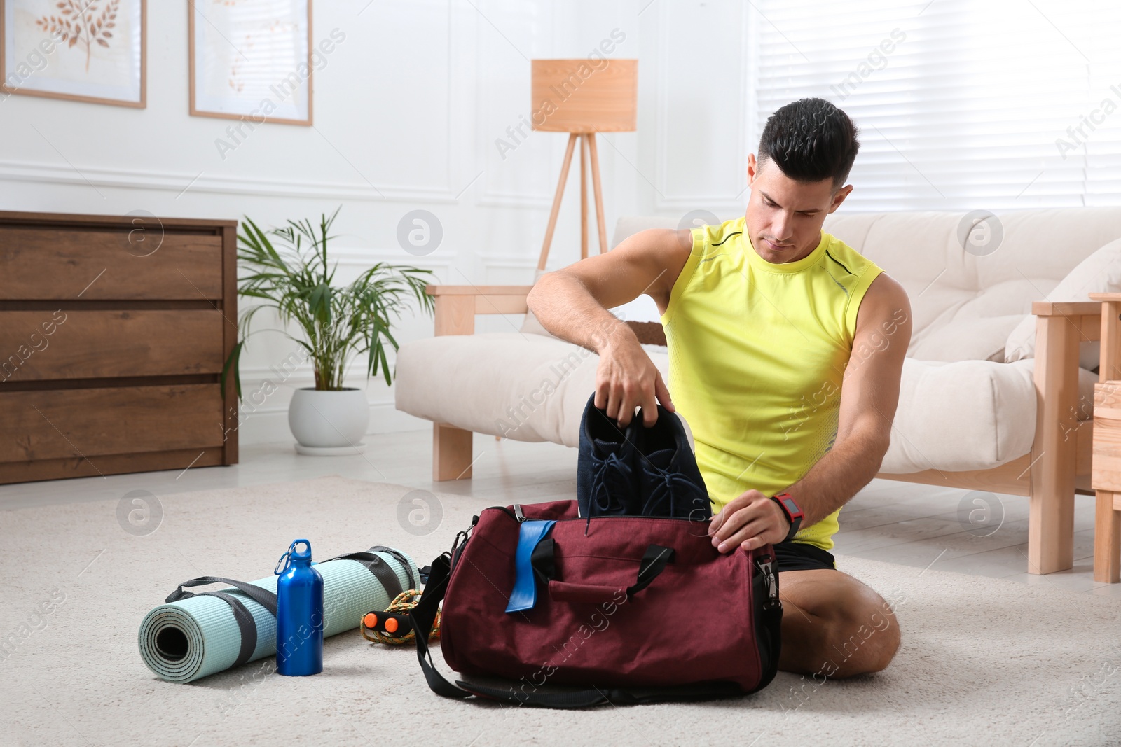 Photo of Man packing sports stuff for training into bag at home