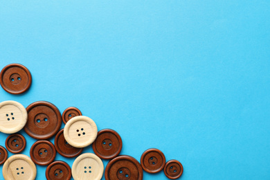 Photo of Many colorful sewing buttons on light blue background, flat lay. Space for text