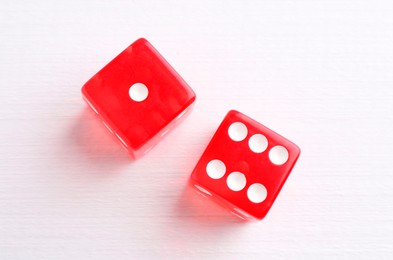 Photo of Two red game dices on white wooden table, flat lay