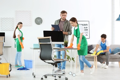 Photo of Team of professional janitors in uniform cleaning office
