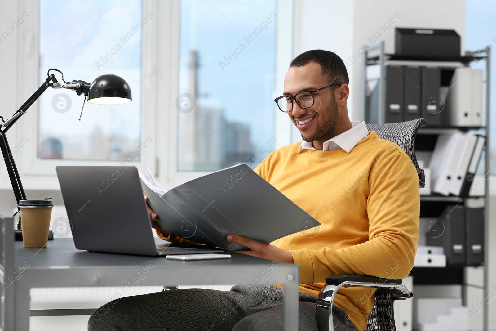 Photo of Young man working with documents at table in office