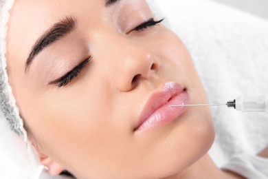 Photo of Young woman getting lip injection in beautician salon, closeup