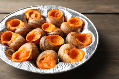 Delicious cooked snails on wooden table, closeup