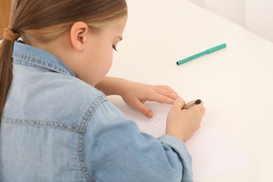 Photo of Girl drawing something with pencil at desk in room, closeup. Home workplace