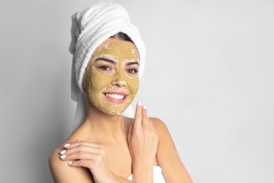 Photo of Young woman with clay mask on her face against light background, space for text. Skin care