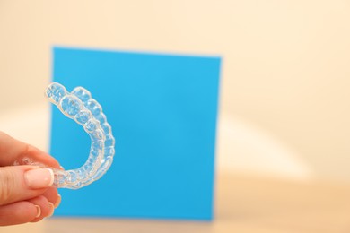 Photo of Woman with transparent dental aligners on blurred background, closeup. Space for text