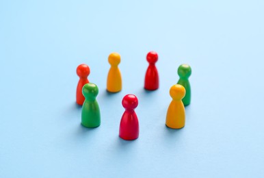 Photo of Colorful pawns on light blue background. Social inclusion concept