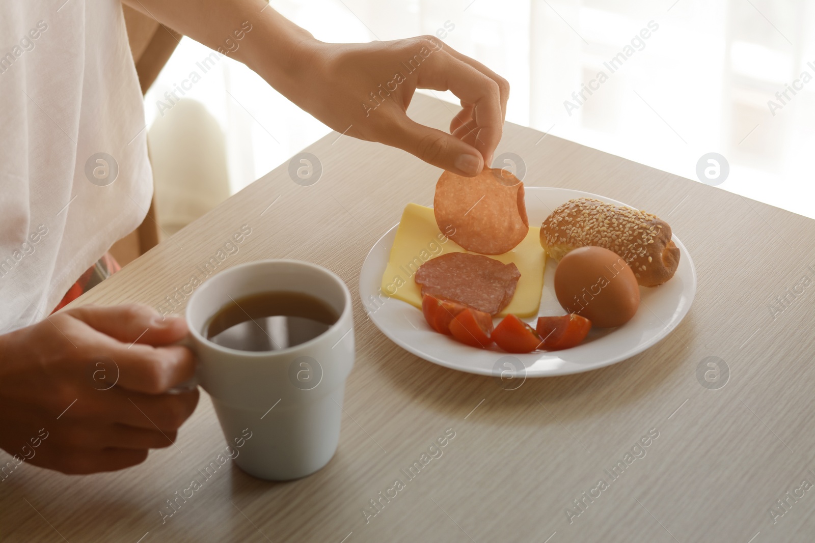 Photo of Woman having tasty nutritious breakfast at wooden table indoors, closeup. Good morning