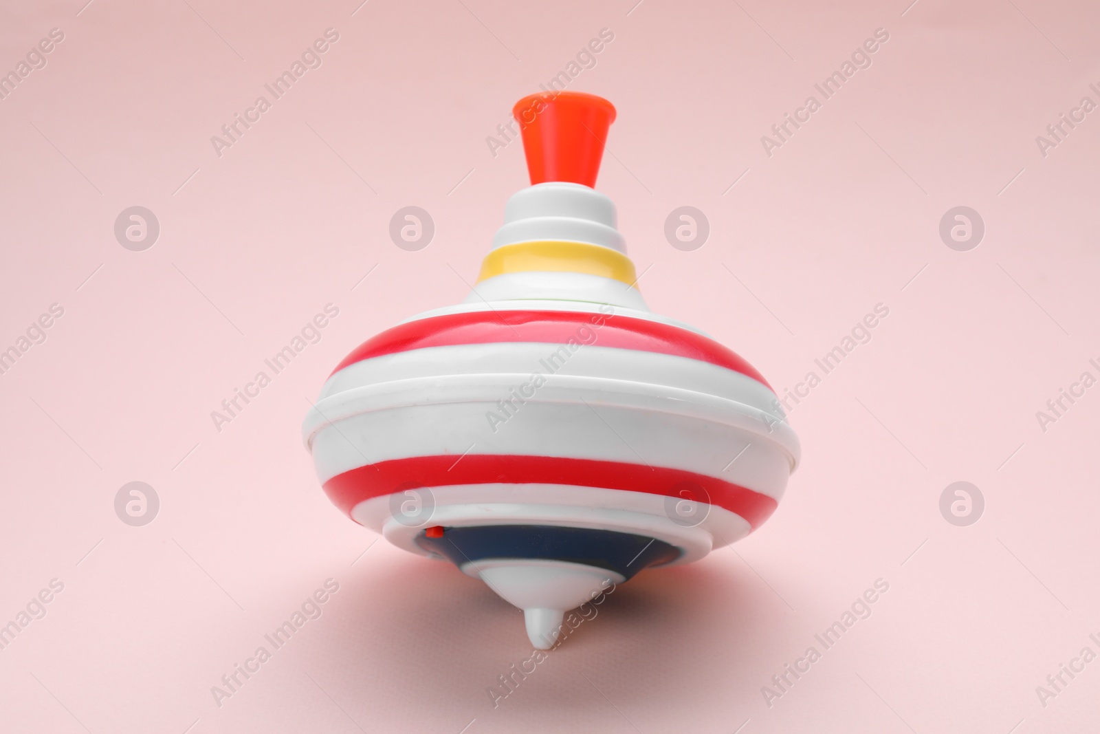 Photo of One bright spinning top on beige background. Toy whirligig