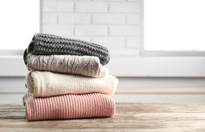 Photo of Stack of warm knitted clothes on table