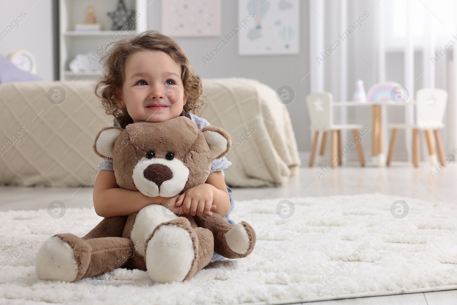 Photo of Cute little girl with teddy bear on floor at home