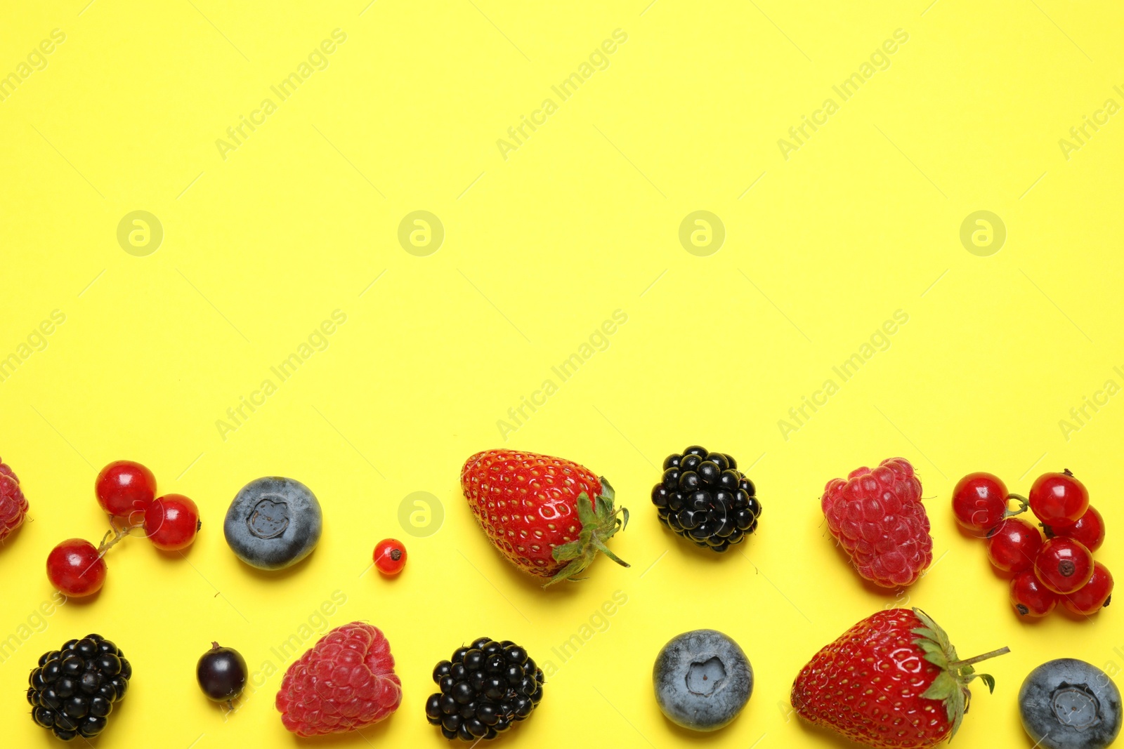 Photo of Mix of fresh berries on yellow background, flat lay. Space for text