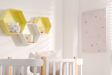 Photo of Hexagon shaped shelves on white wall in nursery. Interior design