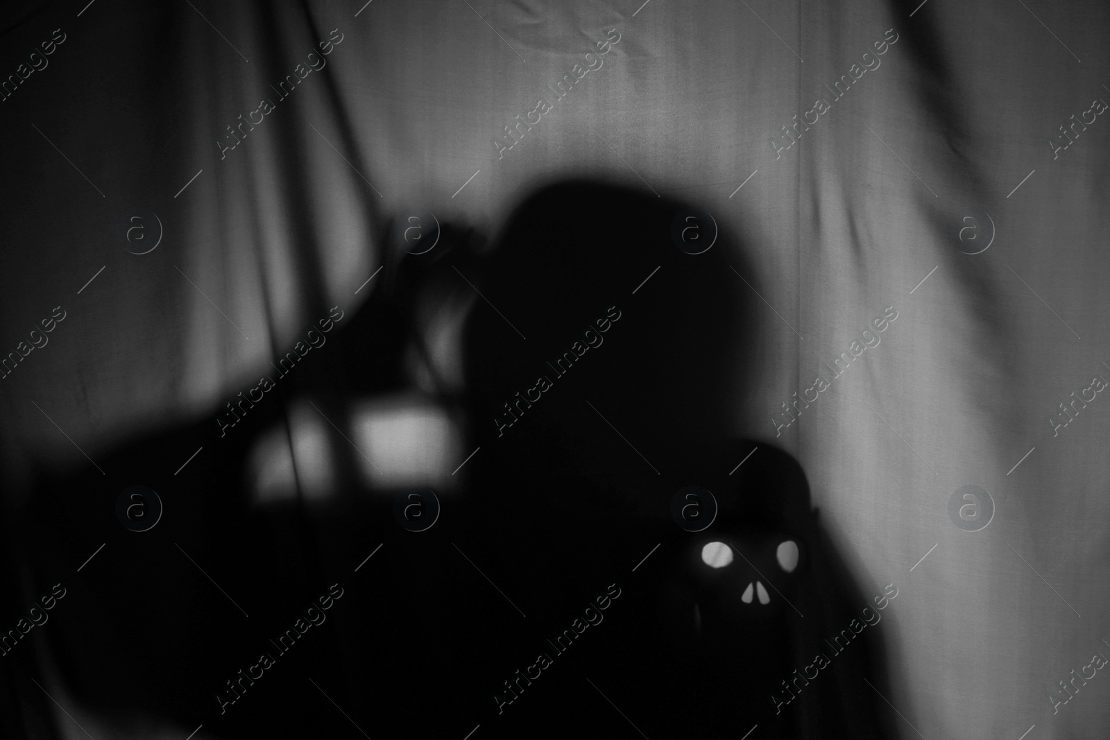 Photo of Silhouette of creepy ghost with skull behind grey cloth