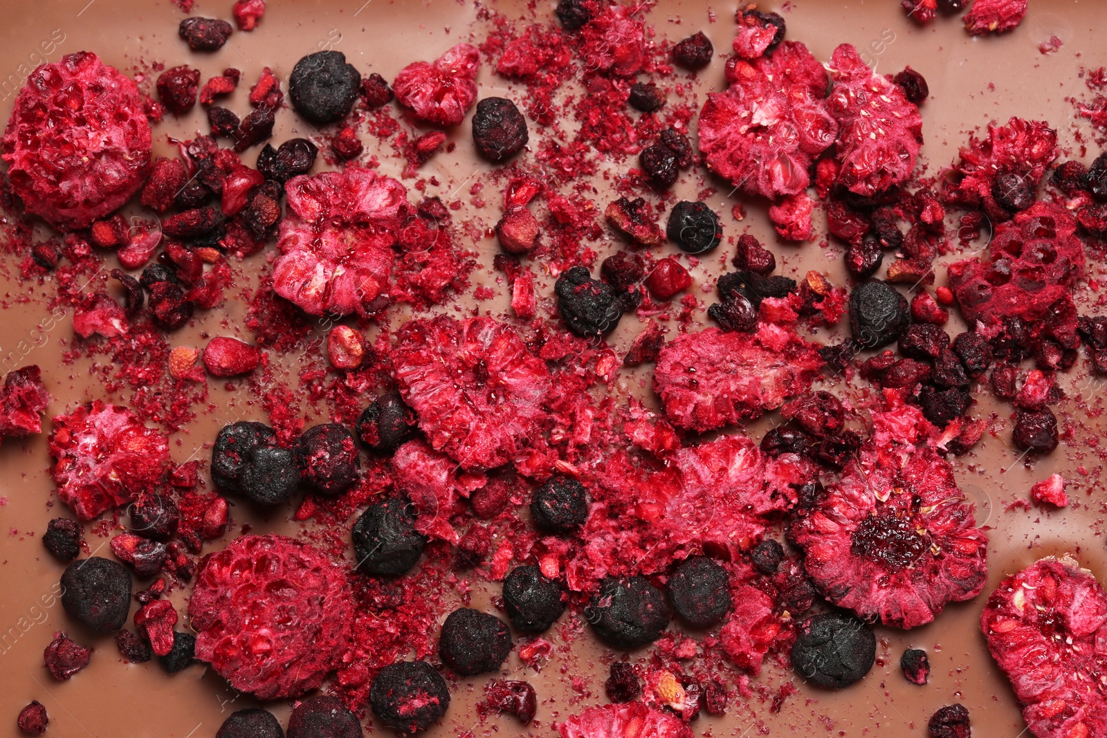 Photo of Chocolate bar with freeze dried berries as background, closeup