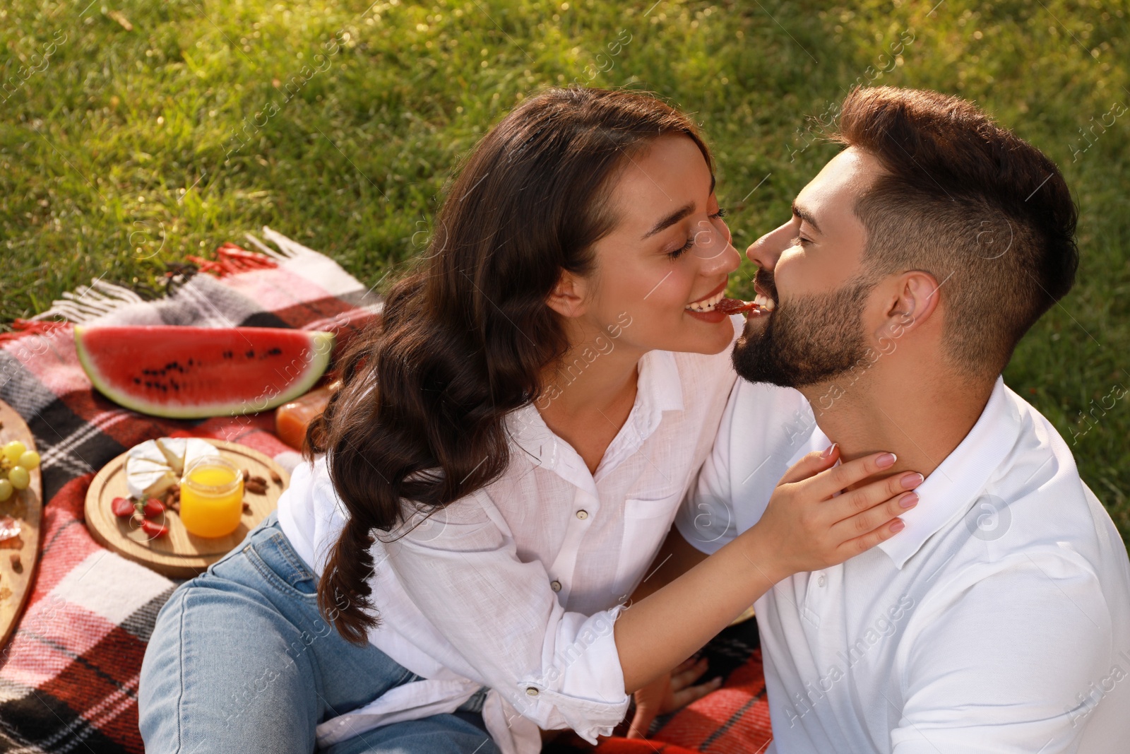 Photo of Lovely couple having picnic on plaid outdoors