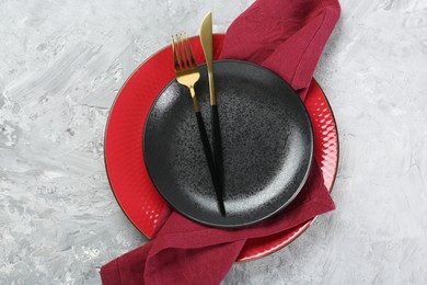 Clean plates, cutlery and napkin on gray textured table, top view