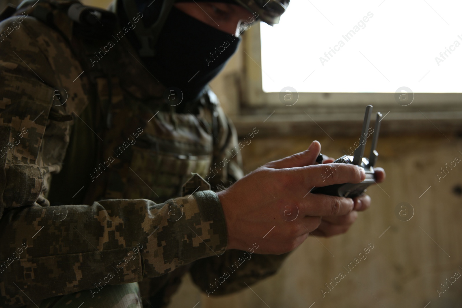 Photo of Military mission. Soldier in uniform with drone controller inside abandoned building