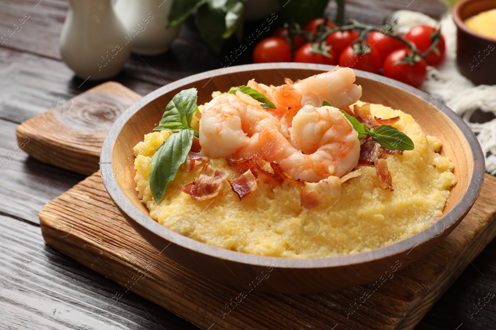 Photo of Fresh tasty shrimps, bacon, grits and basil in bowl on wooden table, closeup