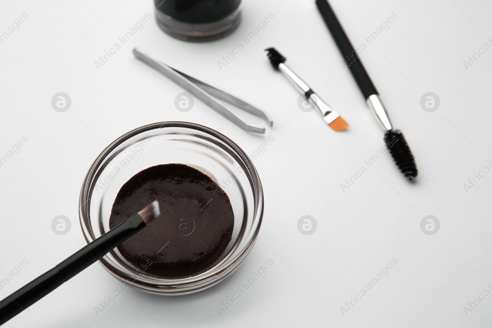 Photo of Eyebrow henna and professional tools on white background, selective focus