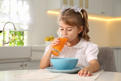 Photo of Little girl having breakfast in kitchen. Getting ready for school