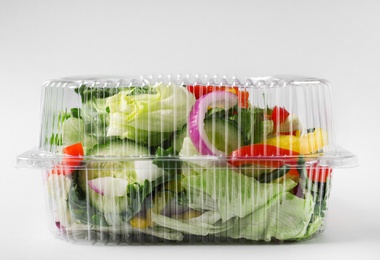 Photo of Plastic container with fresh salad on light grey background