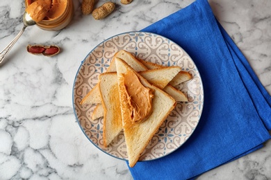 Flat lay composition with peanut butter and toasts on marble background