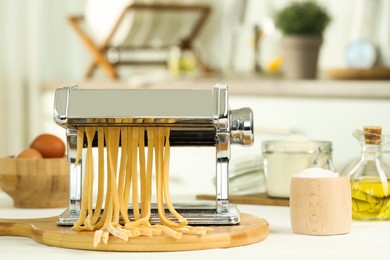 Photo of Pasta maker with raw dough and ingredients on white wooden table