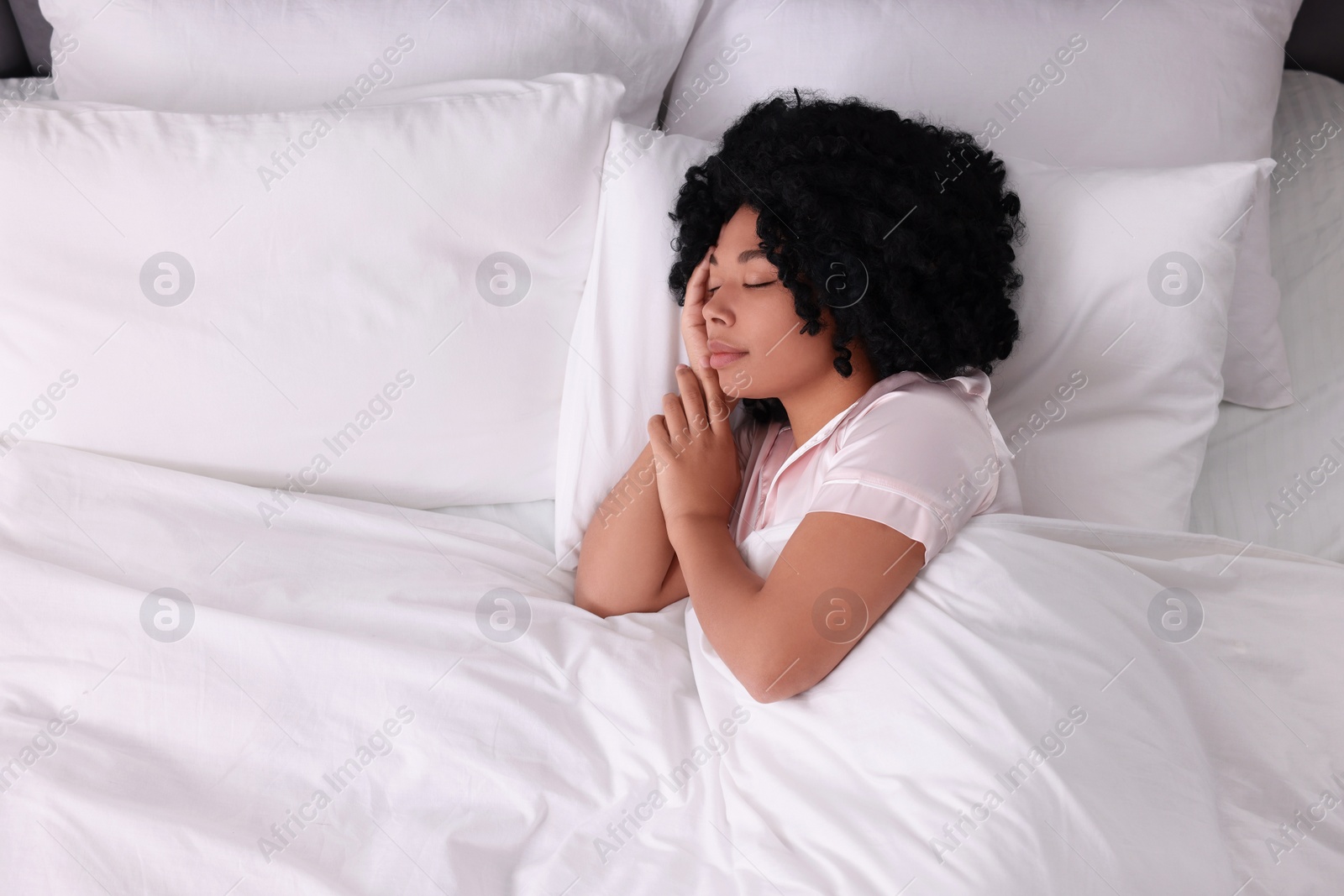 Photo of Beautiful young woman sleeping in soft bed, above view