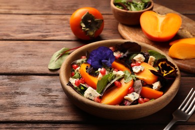 Photo of Delicious persimmon salad with cheese and pomegranate served on wooden table. Space for text
