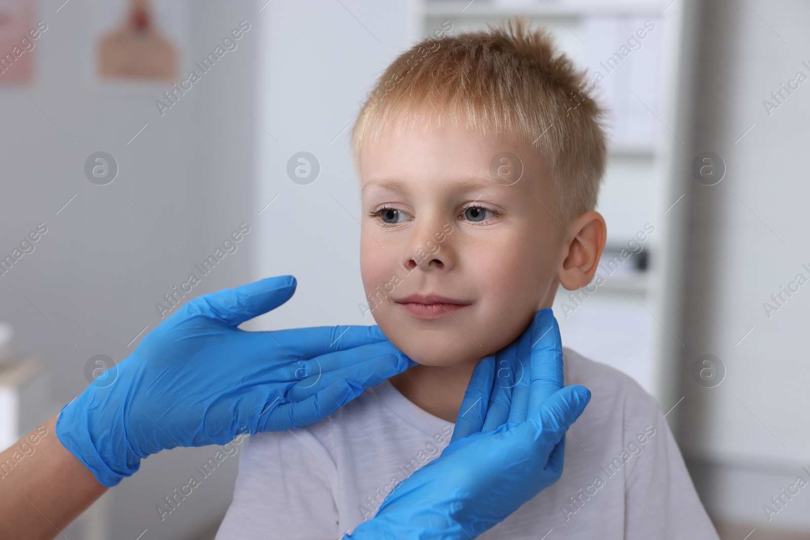 Photo of Endocrinologist examining boy's thyroid gland indoors, closeup