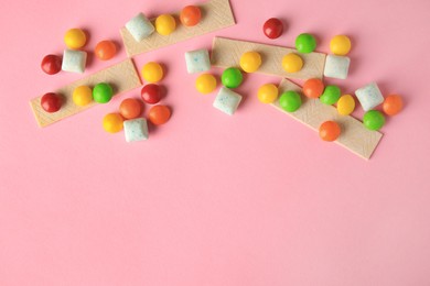 Photo of Different tasty chewing gums on pink background, flat lay. Space for text