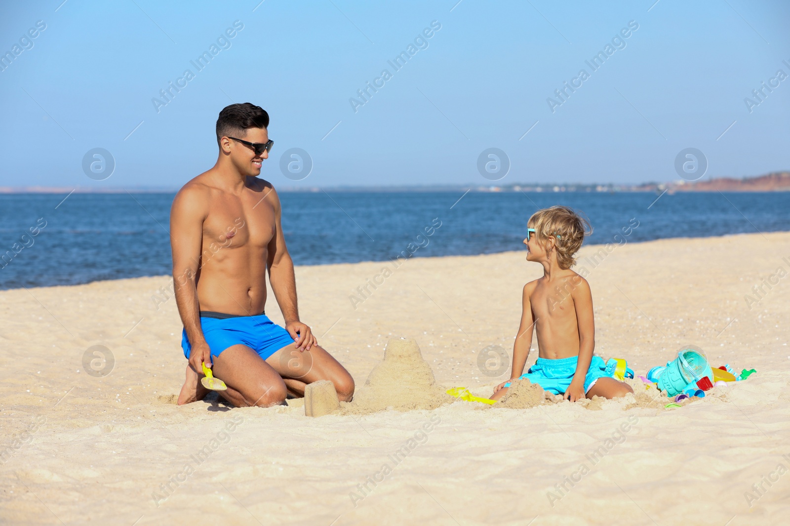 Photo of Father and son playing on sandy beach near sea. Summer holidays with family