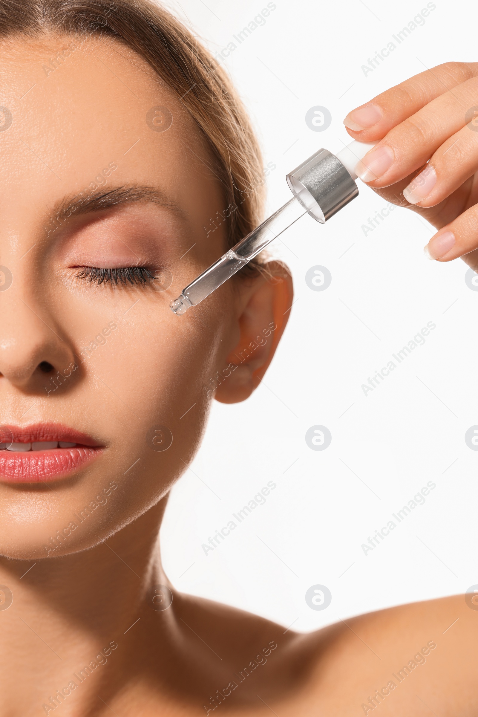 Photo of Woman applying cosmetic serum onto her face on white background, closeup