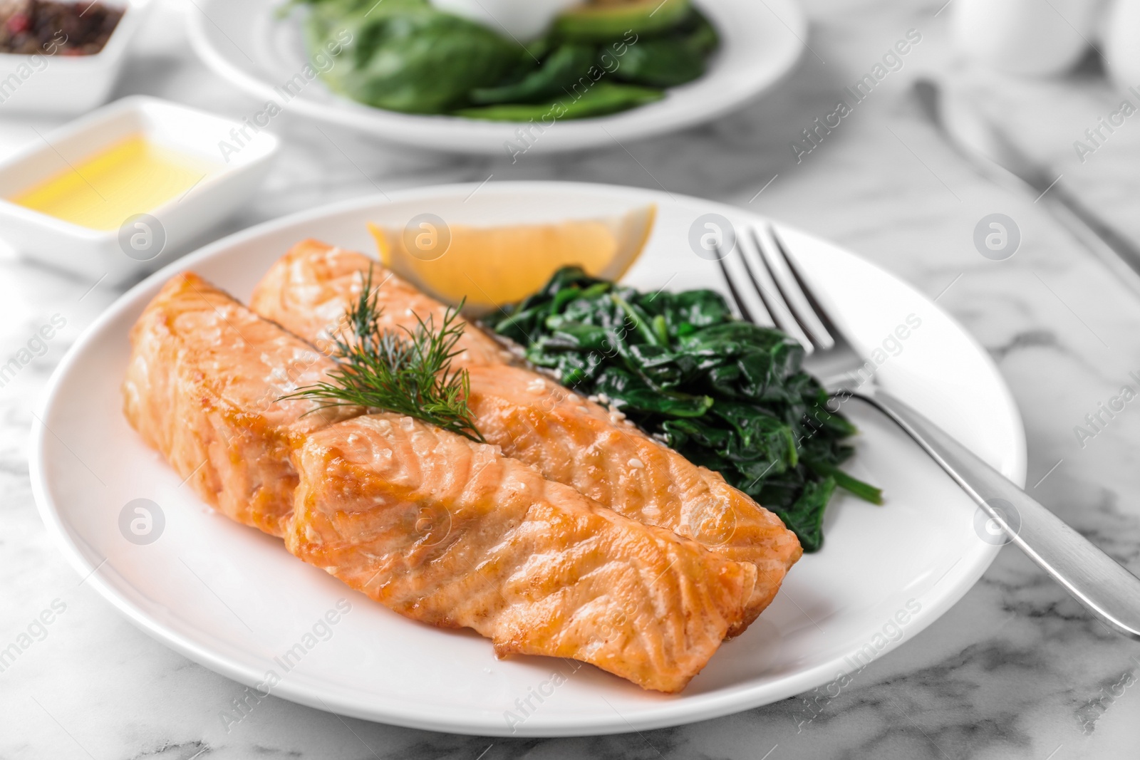 Photo of Tasty salmon with spinach and lemon on table