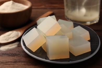 Photo of Agar-agar jelly cubes on wooden table, closeup