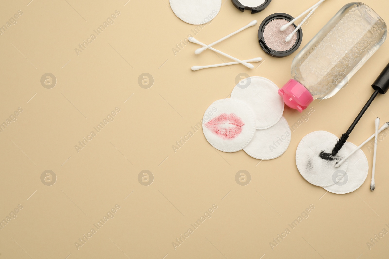 Photo of Dirty cotton pads, swabs, cosmetic products and micellar cleansing water on beige background, flat lay. Space for text