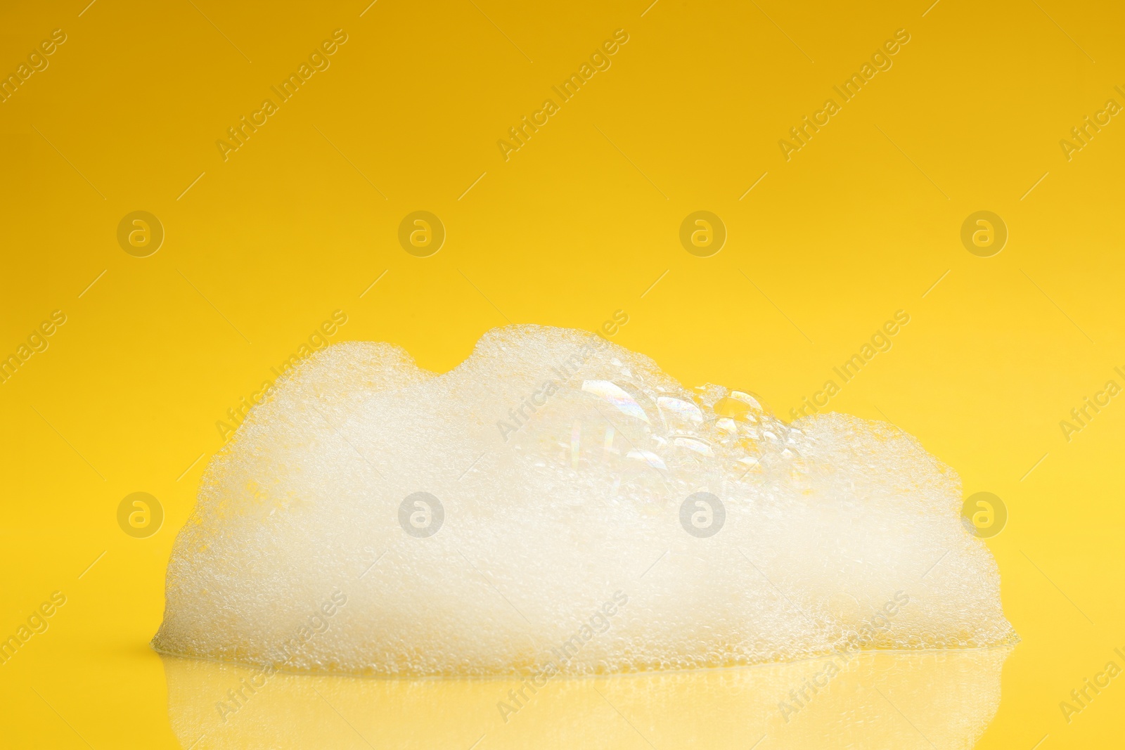 Photo of Drop of fluffy bath foam on yellow background