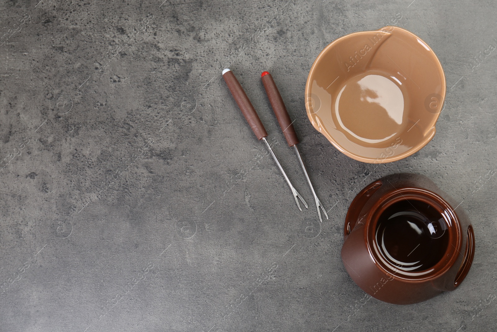 Photo of Fondue set on grey textured table, flat lay. Space for text