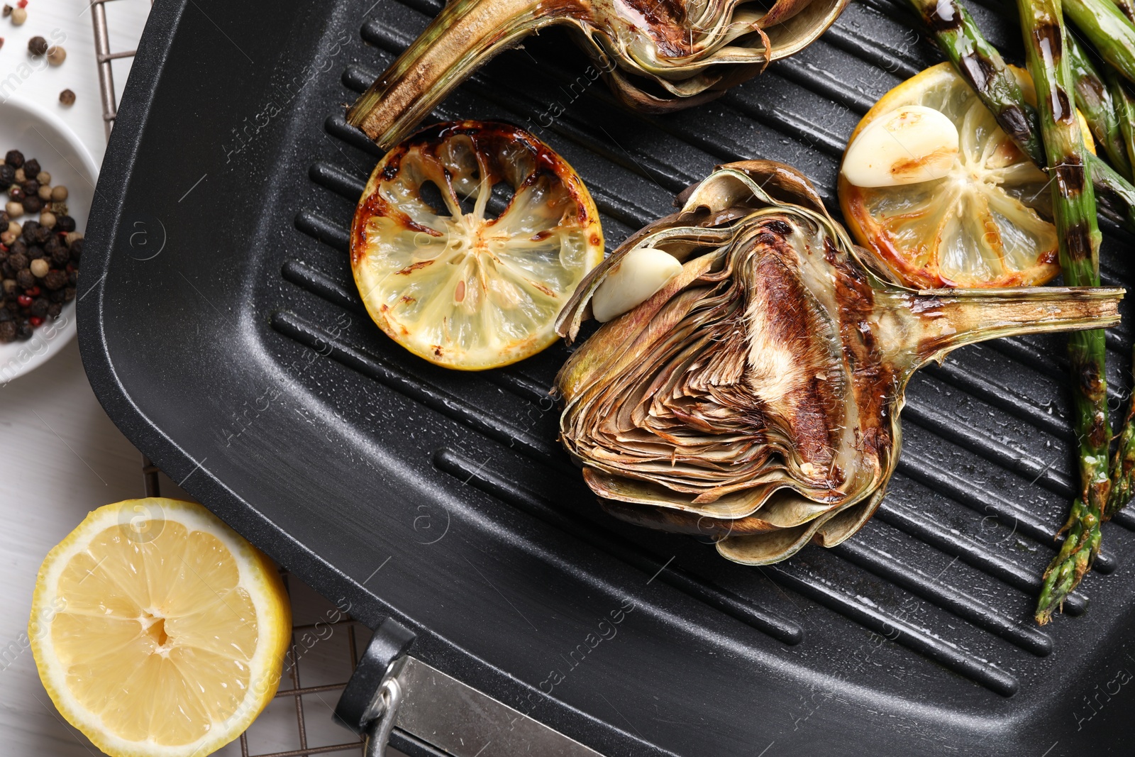 Photo of Tasty grilled artichokes served on white table, flat lay