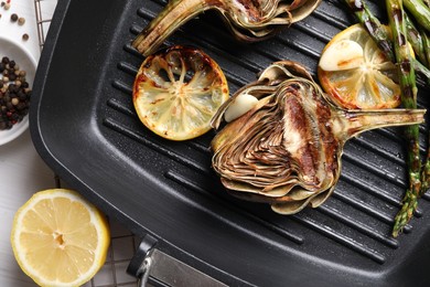 Photo of Tasty grilled artichokes served on white table, flat lay