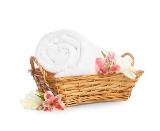 Photo of Wicker basket with rolled bath towels and beautiful flowers isolated on white