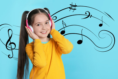 Cute girl listening to music through headphones on light blue background
