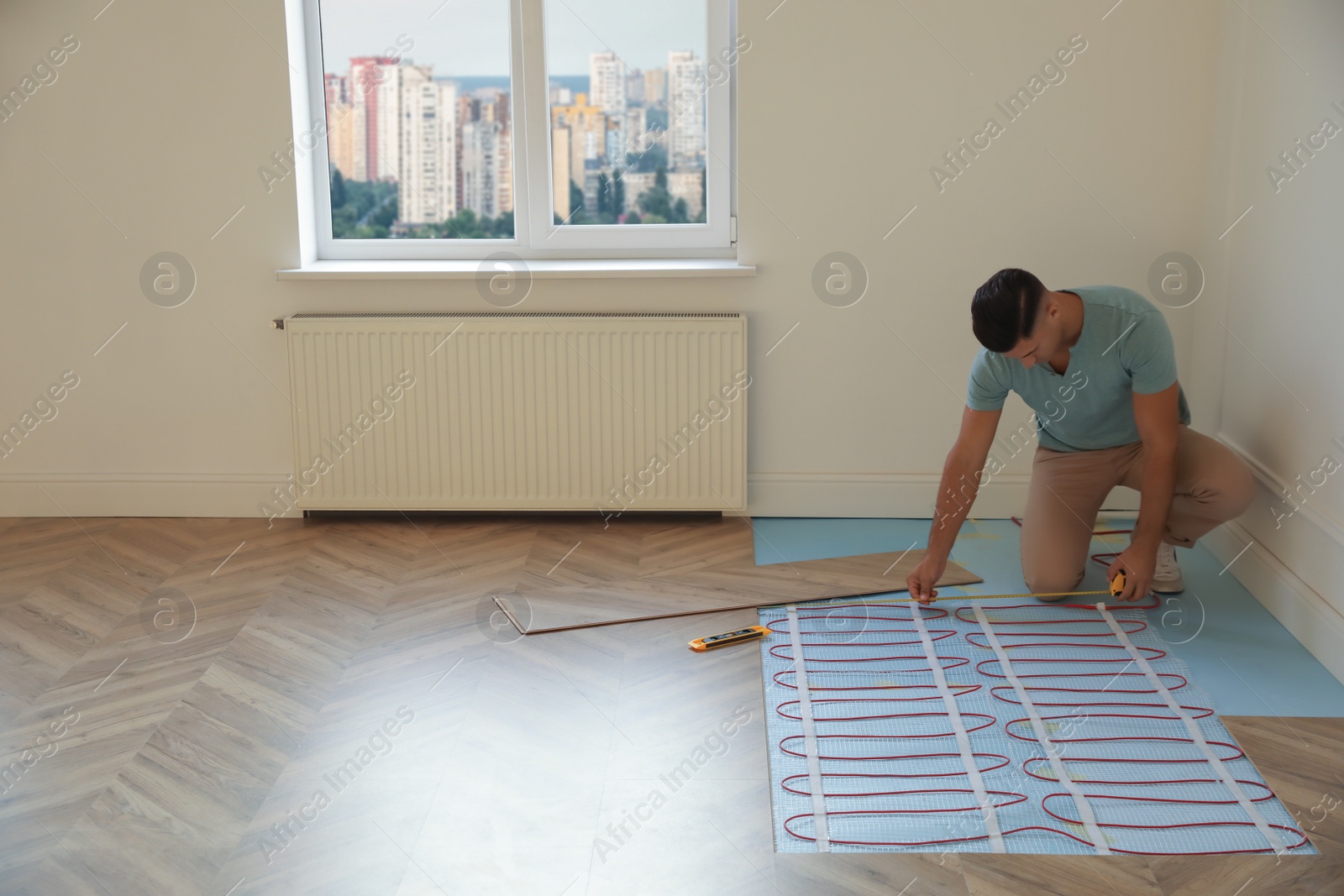 Photo of Professional worker installing electric underfloor heating system indoors