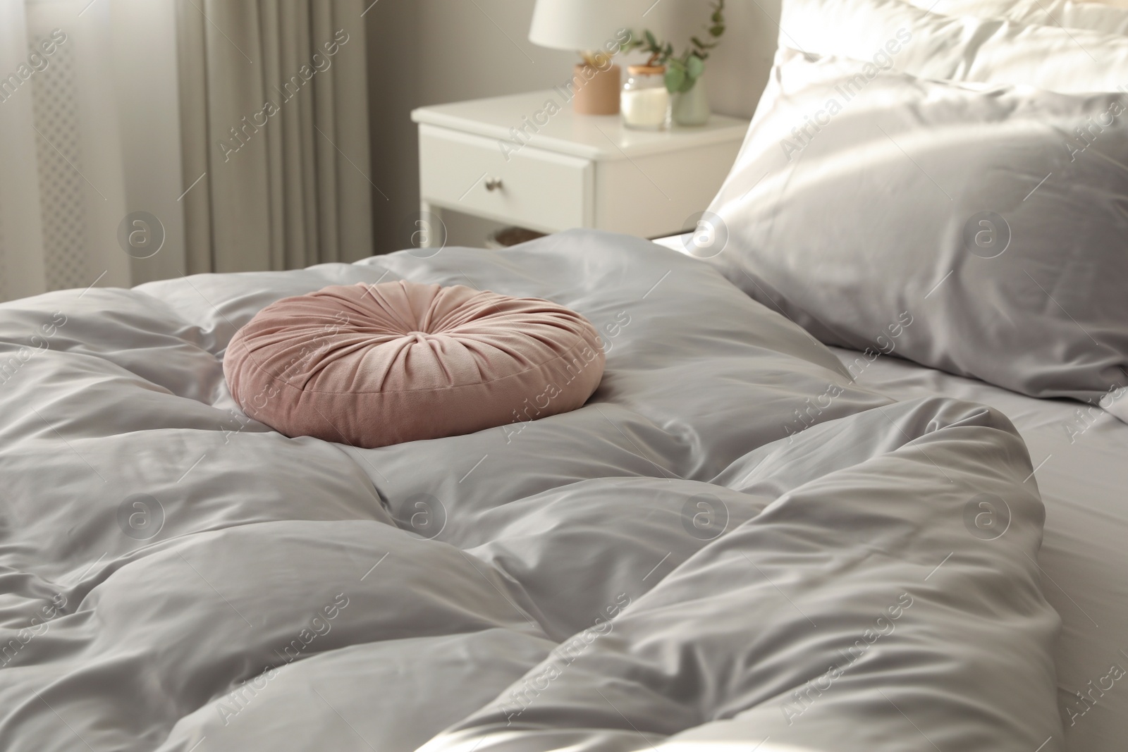 Photo of Bed with stylish silky linens in room